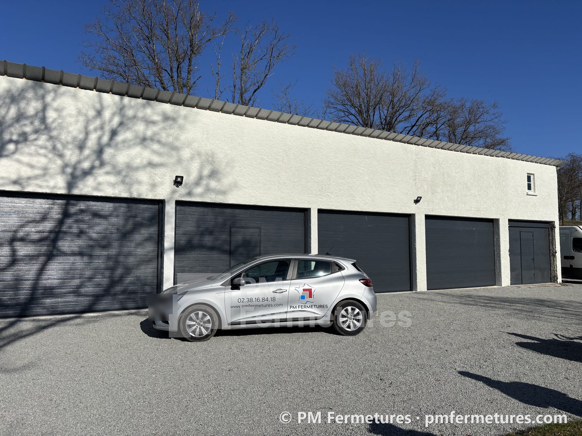 Rangée de garages équipés de portes sectionnelles, avec un véhicule PM Fermetures