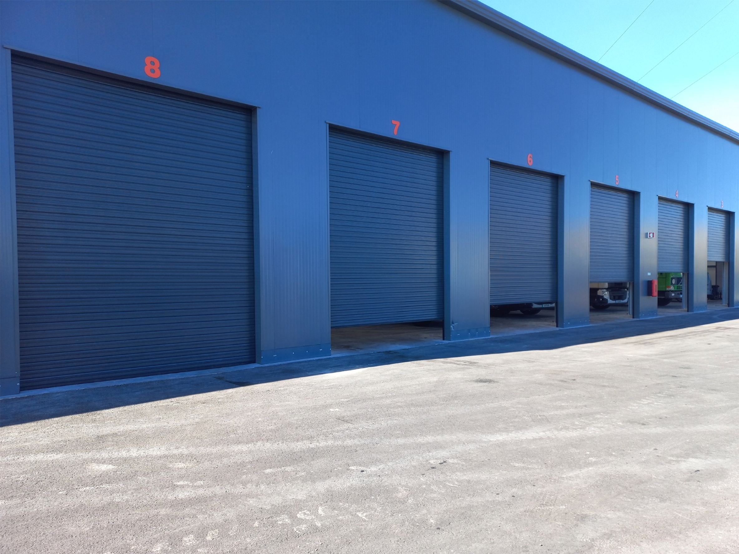 Rangée de portes de garage enroulables bleues sur bâtiment industriel