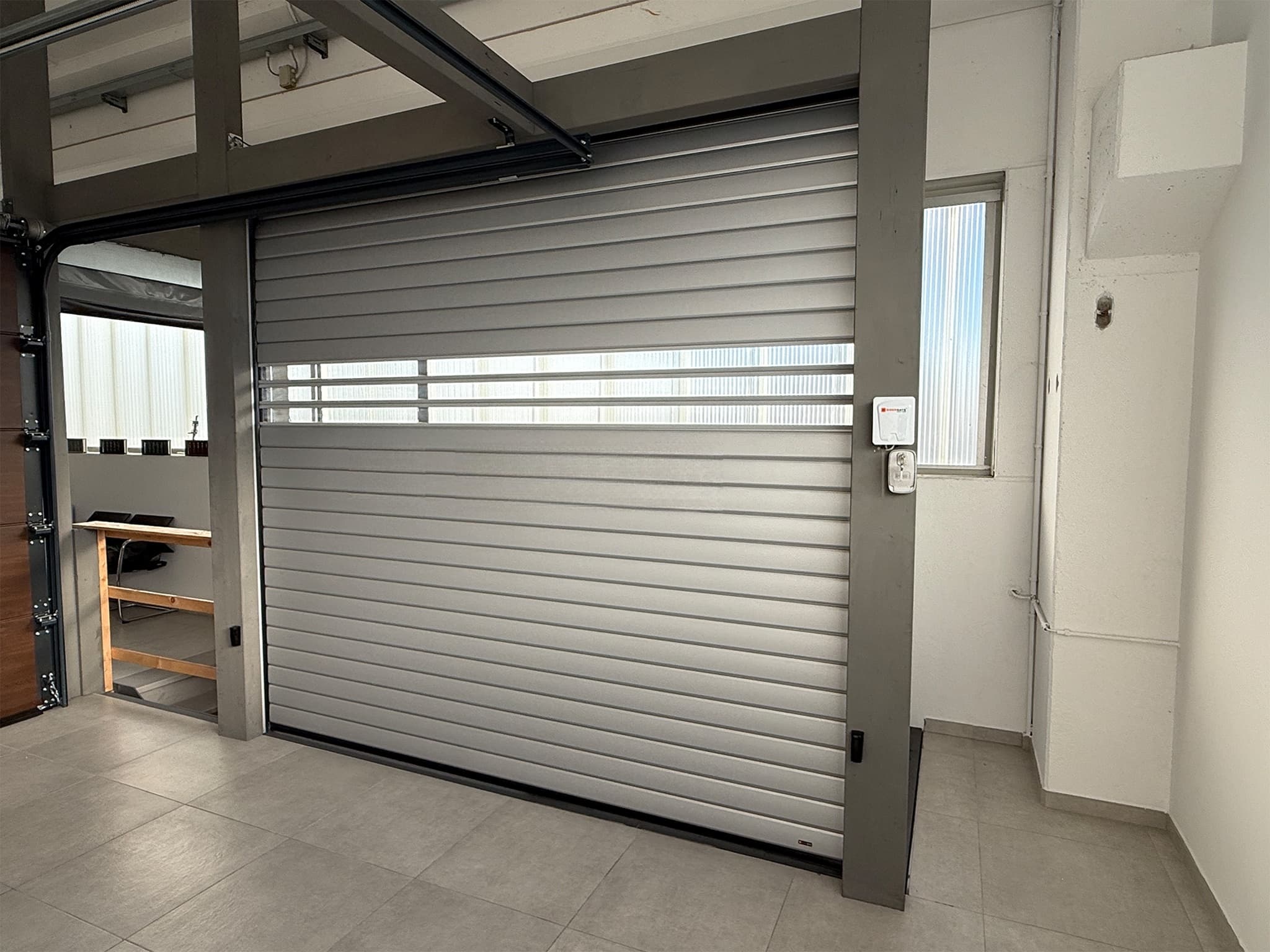 Porte de garage enroulable en lames acier gris métallique installée en intérieur