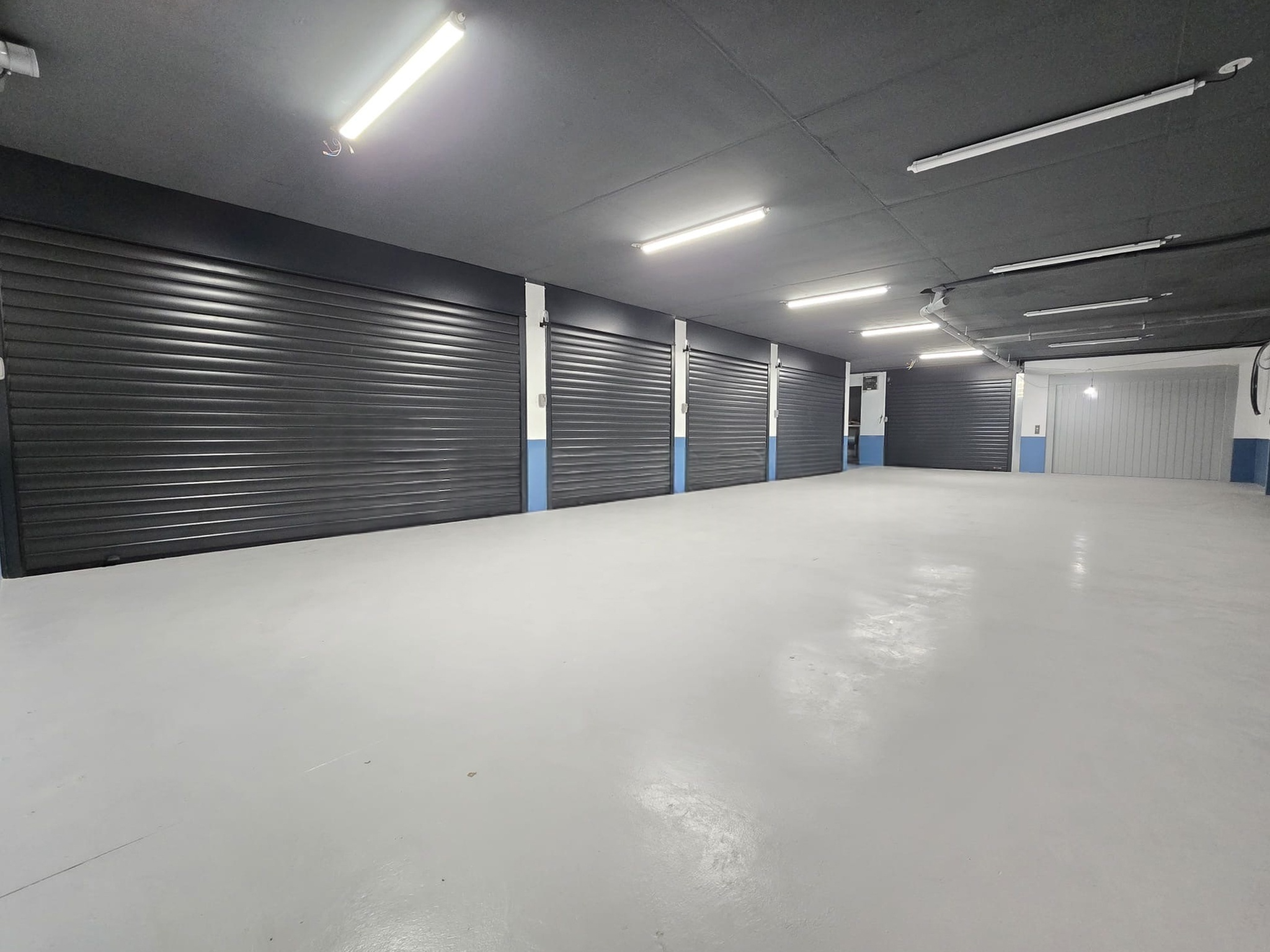 Parking collectif avec alignement de boxes à portes enroulables anthracite