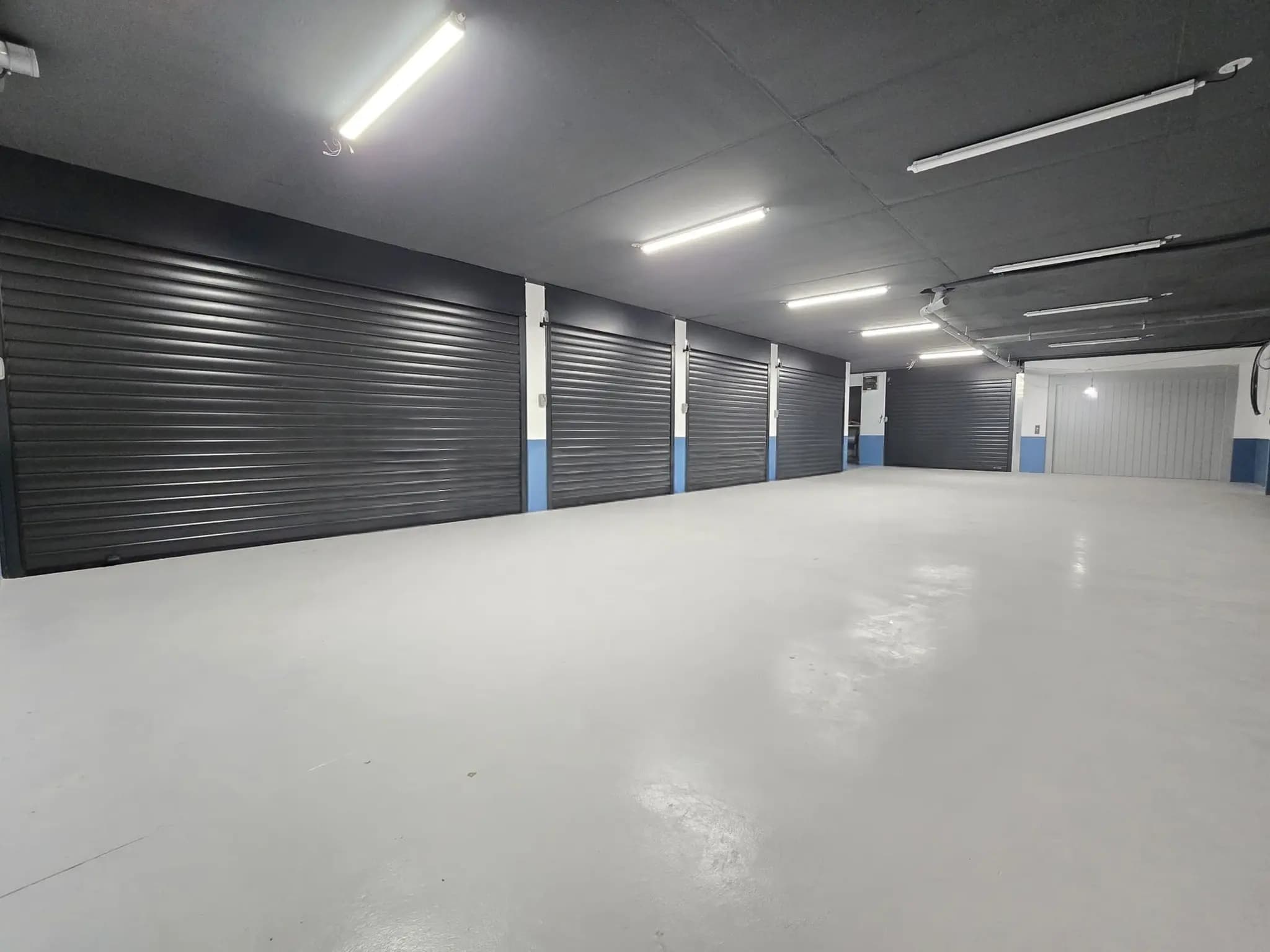 Parking collectif avec alignement de boxes à portes enroulables anthracite