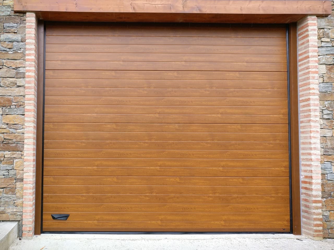 Porte de garage sectionnelle imitation bois chêne clair, entourage en brique
