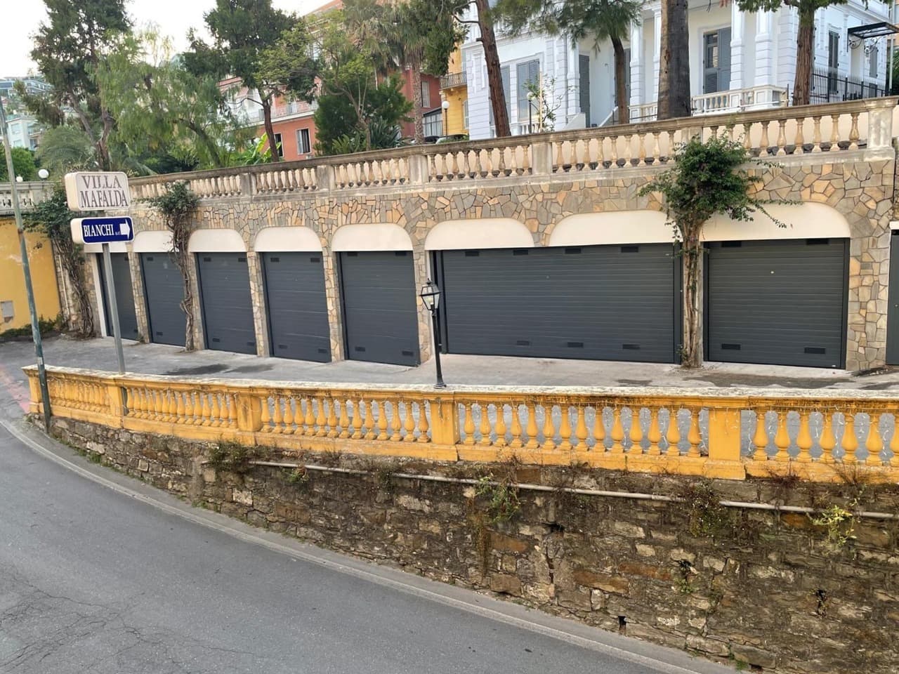 Rangée de boxes de garage à portes sectionnelles grises sous arcades en pierre