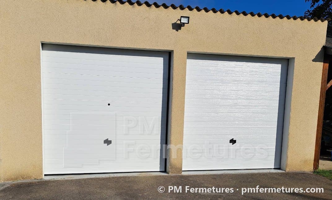 Deux portes de garage sectionnelles blanches sur une façade crépie
